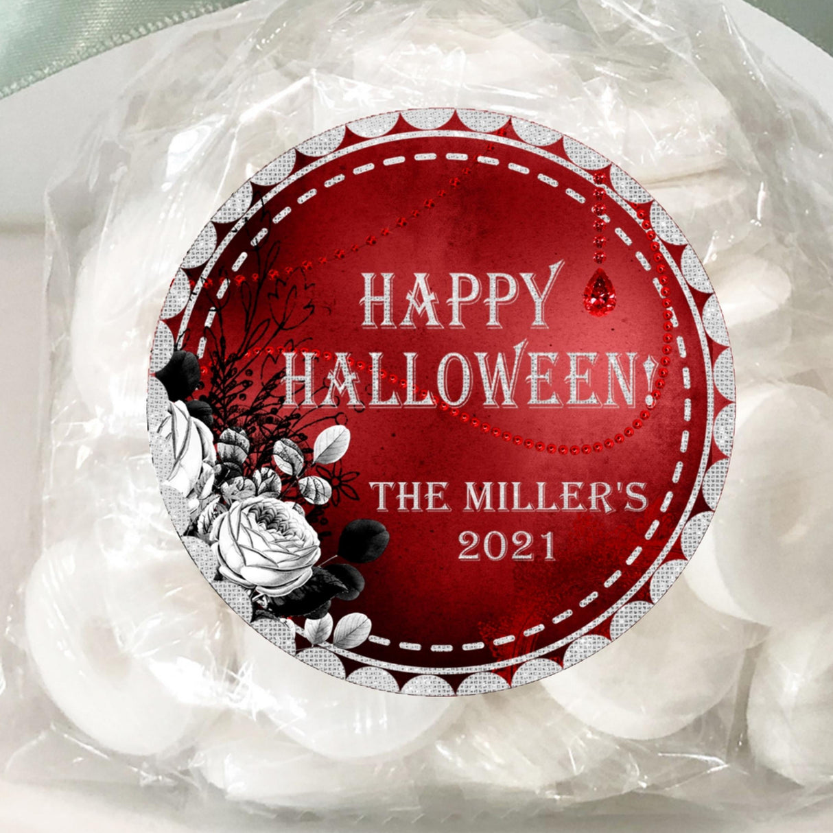 round halloween sticker with silver lettering over red background and floral illustration