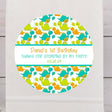 Cute dinosaur birthday sticker with teal and orange baby dinosaurs