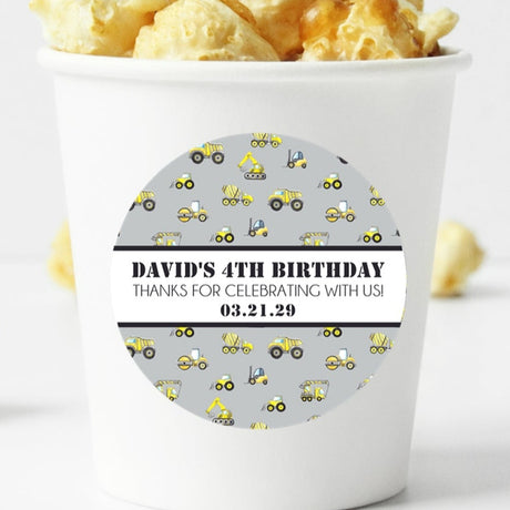 Grey construction birthday sticker with yellow trucks and personalized name