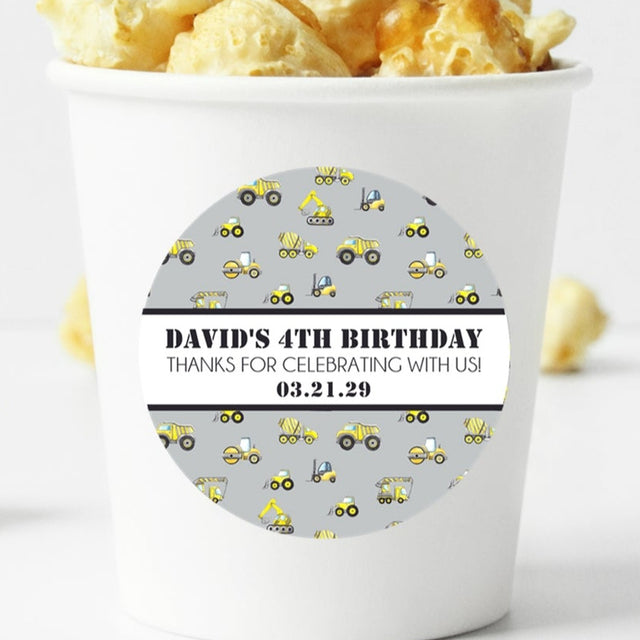Grey construction birthday sticker with yellow trucks and personalized name