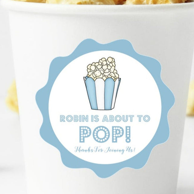 blue popcorn baby shower sticker with “About to Pop” design